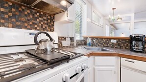 Una cocina moderna equipada con estufa a gas, hervidor, cafetera y lavavajillas.