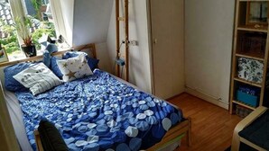 Un dormitorio con cama, armario, escritorio y ventana con vistas a la vegetación.