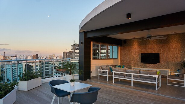 Un espace de vie extérieur moderne comprenant un coin repas, des sièges et une vue sur la ville.