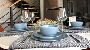 Un coin repas avec une table dressée pour quatre personnes, agrémenté de bols bleus et de verres à vin.