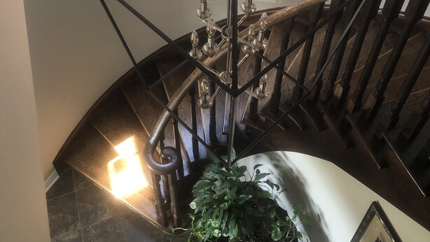 A staircase with a wrought iron railing and a chandelier. - Willow Pond Bed and Breakfast  (Port Perry)