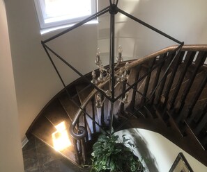 A staircase with a wrought iron railing and a chandelier. - Willow Pond Bed and Breakfast  (Port Perry)