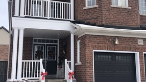 A two-story brick house with a front porch, a garage, and a Christmas wreath. - Willow Pond Bed and Breakfast  (Port Perry)