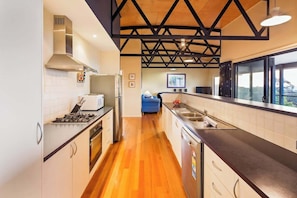 Una cocina moderna con techo de madera, electrodomésticos de acero inoxidable y vistas amplias a través de grandes ventanales.