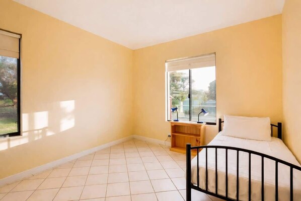 A room with a bed, a window, and a view of the outdoors.