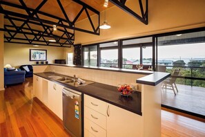 A modern kitchen with a large island, a dishwasher, and a view of the outdoors.