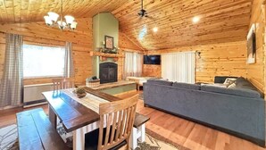A cozy cabin interior with a wooden dining table, a sofa, and a fireplace. - Hot Tub  | Fire Pit | 32 Miles to YNP | Fox Den Cabin (Island Park)