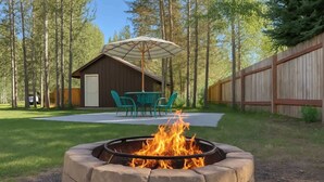 A backyard with a stone fire pit, outdoor seating, and a wooden building. - Hot Tub  | Fire Pit | 32 Miles to YNP | Fox Den Cabin (Island Park)