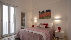 A bedroom with a bed, a nightstand, a red lamp, a painting on the wall, and a sliding door. - Puglia holiday apartment in Monopoli (Monopoli)