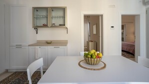A modern kitchen with white cabinets, a beige countertop, and a fruit bowl on the table. - Puglia holiday apartment in Monopoli (Monopoli)