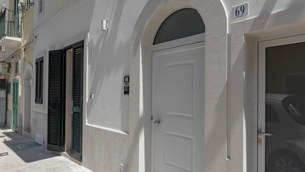 A white building with a large arched doorway and a door with a number 69 sign above it. - Puglia holiday apartment in Monopoli (Monopoli)