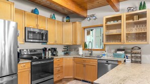 A modern kitchen with wooden cabinets, stainless steel appliances, and a granite countertop.