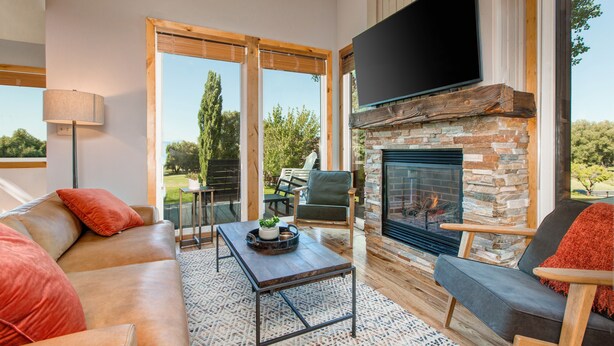 Una sala de estar moderna con chimenea, sofá de cuero y televisor montado en la pared.