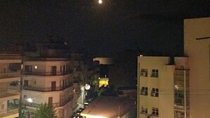 Vista nocturna de un paisaje urbano con edificios y una luna visible.