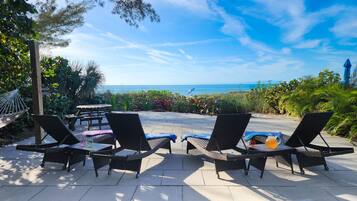 Une terrasse avec mobilier d’extérieur donnant sur une plage.