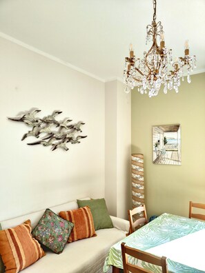 A dining area with a chandelier, a wall-mounted artwork of birds, and a view of a deck through a window.