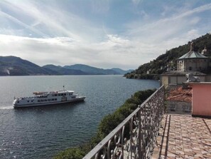 Un bote en un lago tranquilo con montañas al fondo y un edificio con techo verde a la derecha.