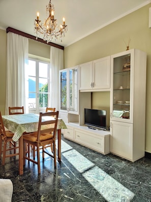 A dining area with a table, chairs, a chandelier, a television, and cabinets.