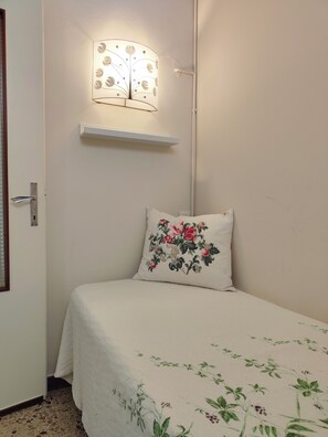 A room with a bed, a wall-mounted light fixture, and a door.