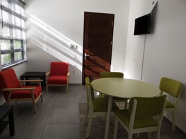 Una habitación con puerta de madera, un televisor en la pared y una mesa con sillas.
