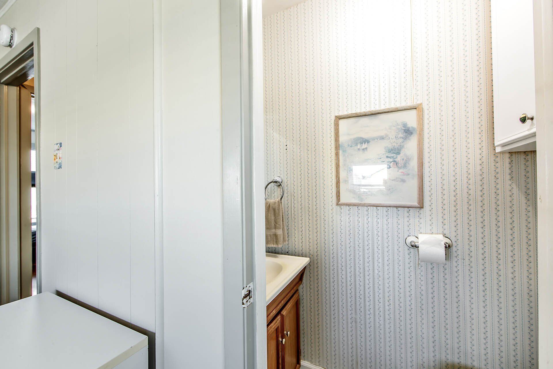 Ein Badezimmer mit Waschbecken, Toilette und einem gerahmten Bild an der Wand.