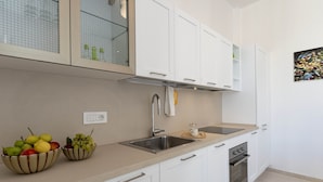 A modern kitchen with white cabinets, a stainless steel sink, and a built-in oven. - Historic citycentre apartment with breathtaking views (Monopoli)