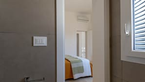 A hotel room with a bed, a door, and a window with blinds. - Historic citycentre apartment with breathtaking views (Monopoli)