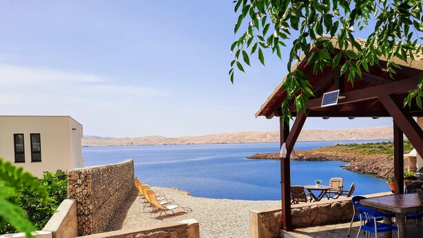 A terrace with a view of a lake, stone walls, and outdoor seating. - Villa Mihaela - Beachfront apartment "Mario" with sea view and pool (Cesarica)