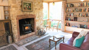 A cozy living room with a stone fireplace, a bookshelf filled with books, a red sofa, and a wooden coffee table.