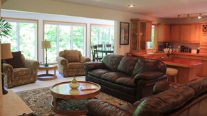 A spacious living room with leather sofas, a coffee table, and a dining area with wooden cabinets. - Lake Front spacious family home (Eagle Rock)