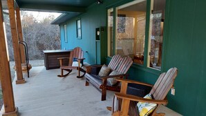 A porch with wooden rocking chairs and a bench, a small table, and a wooden cabinet. - Lake Front spacious family home (Eagle Rock)
