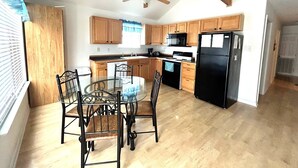 A kitchen with wooden cabinets, a black refrigerator, a stove, and a ceiling fan. - La Bon Vie - Coastal Realty Group (Grand Isle)