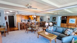 A spacious living room with a large sofa, a coffee table, and a dining area with chairs and a table. - AMAZING VIEW!  1 Back from Oceanfront 1bed/2 bath (Lahaina)