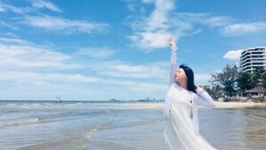 A beach scene with a person in a white dress, a clear sky, and buildings in the background. - Goodtimes Pool Villa 2 (Walk TO Beach) (Hua Hin)