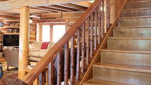 A wooden staircase with a railing leading to a loft area. -  Rustic Log Lodge Overlooking Water and Mountain Views (Stanley)
