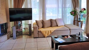 A modern living room with a flat-screen TV, a sofa, a coffee table, and a fireplace. - Elegant Vouliagmeni apartment in a Unique Spot. (Vouliagmeni)