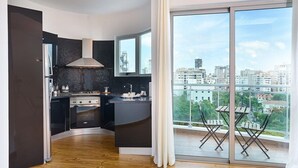 Una cucina moderna con schienale nero, elettrodomestici in acciaio inossidabile e un'ampia finestra con vista sulla città.