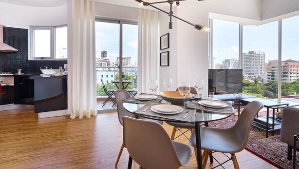 Zona pranzo moderna con tavolo in vetro, sedie e vista sulla città.