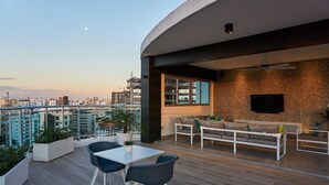 Un'area esterna moderna con zona pranzo, posti a sedere e vista sulla città.