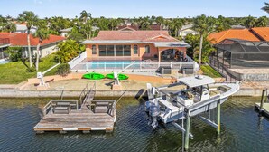 A house with a swimming pool, dock, and green kayaks. - Water Front Home with Heated Pool & Hot Tub, 2 Master Suites & a Floating Dock (New Port Richey)