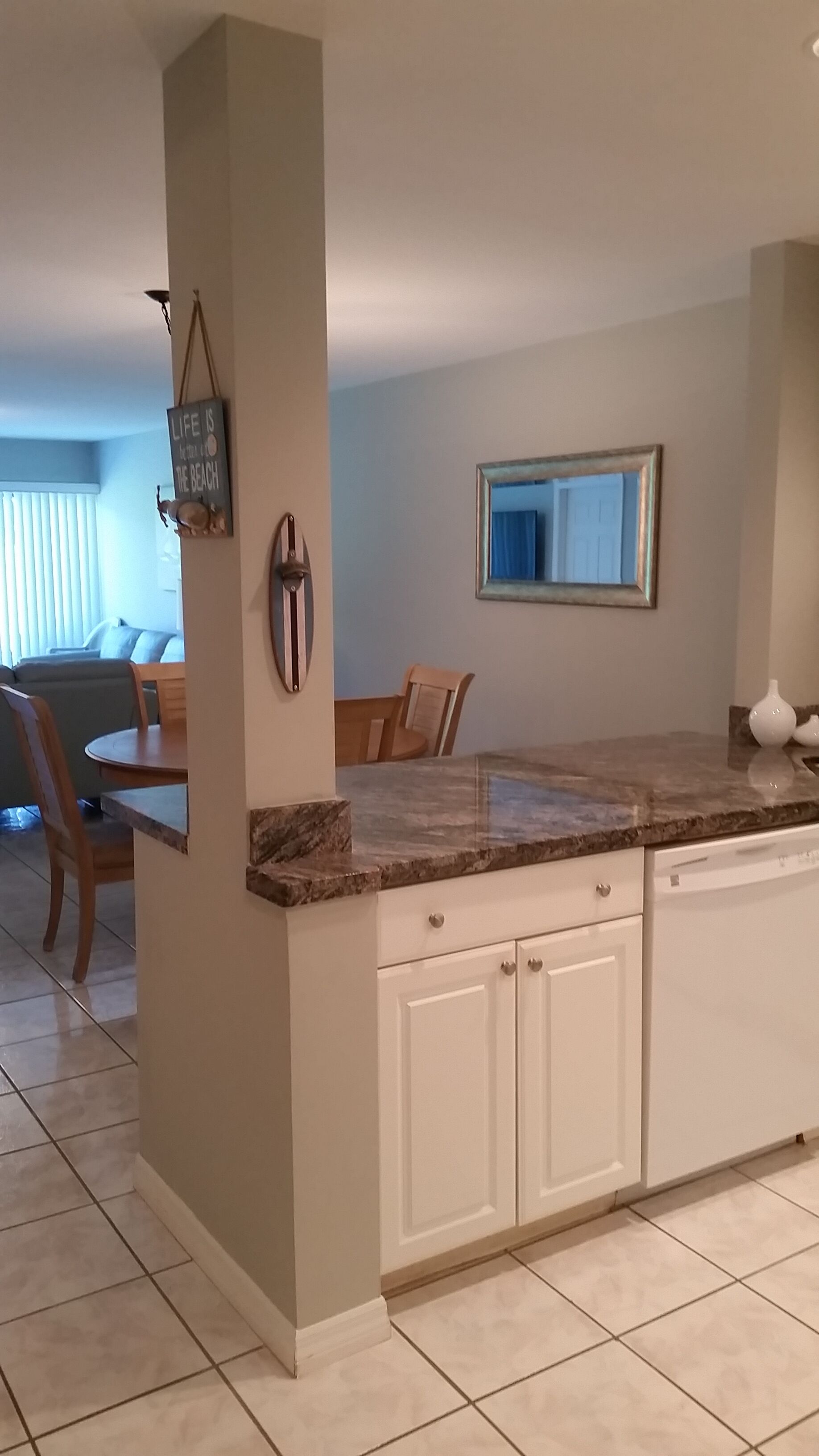 A kitchen with white cabinets, a marble countertop, and a dining area with a table and chairs.