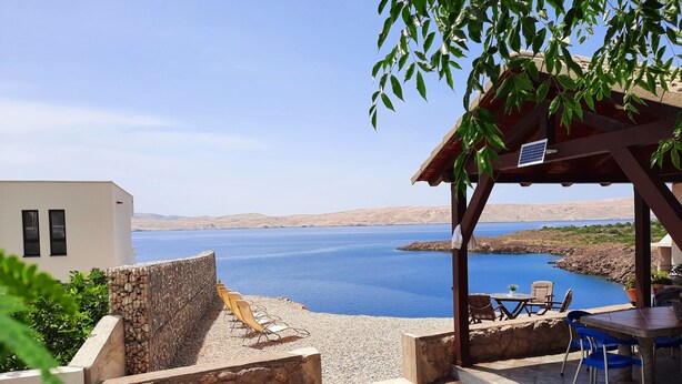 A terrace with a view of a lake, stone walls, and outdoor seating. - Villa Mihaela - Beachfront apartment "Ika" with sea view and pool (Cesarica)