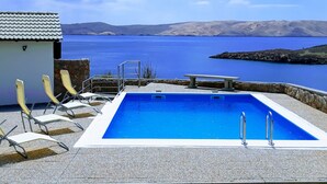 En swimmingpool med utsikt över en stor sjö eller ett hav och avlägsna kullar.