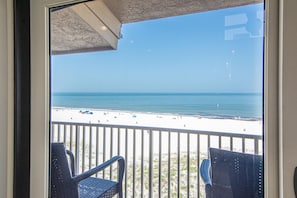 Ein Balkon mit zwei Stühlen mit Blick auf einen Strand.