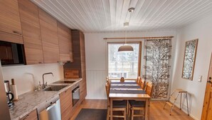 Eine moderne Küche mit Holzausbau, einem Edelstahl-Geschirrspüler und einem Essbereich mit Tisch und Stühlen.