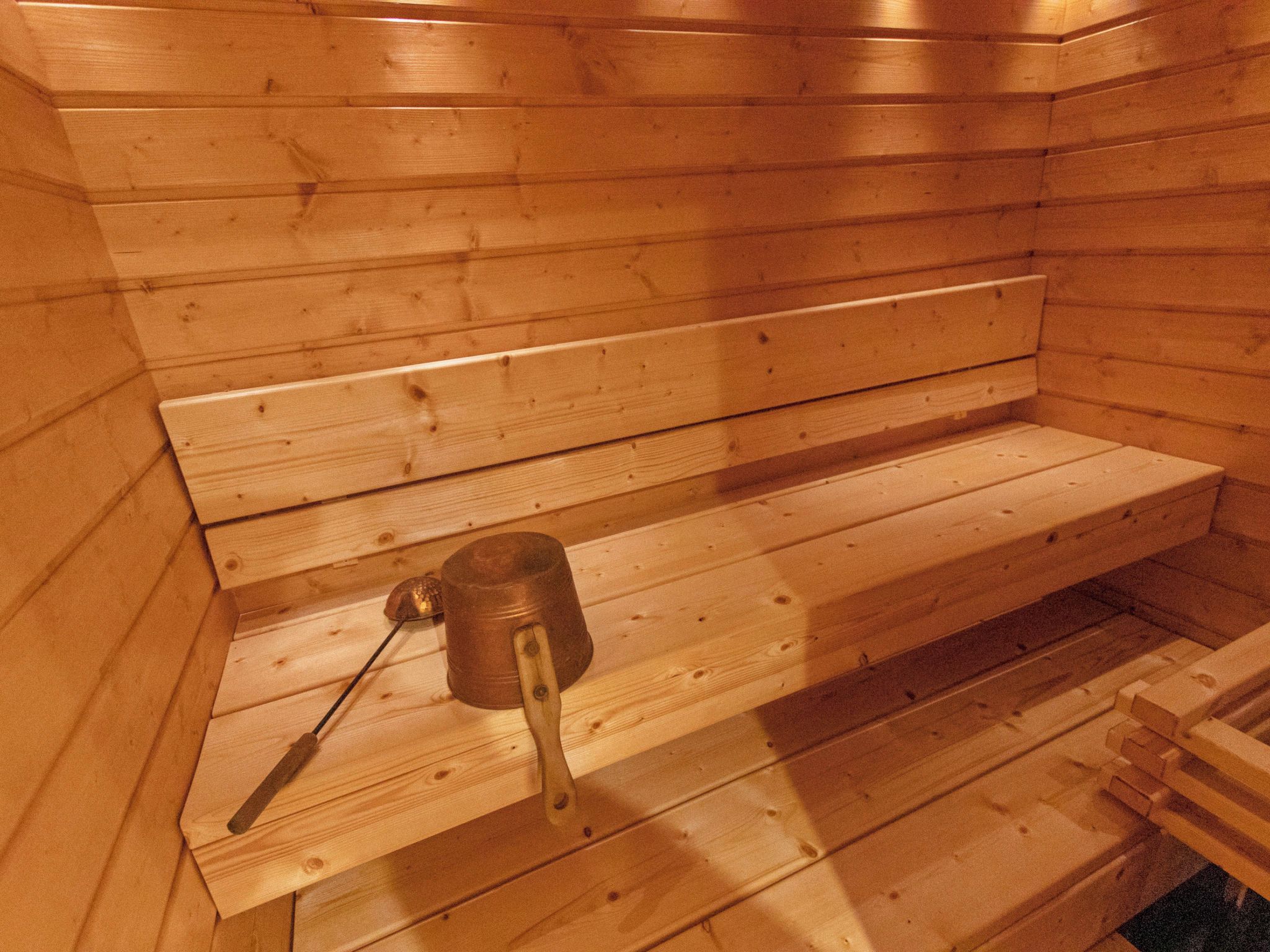 Eine Saunabank aus Holz mit einer Bürste und einem Behälter.