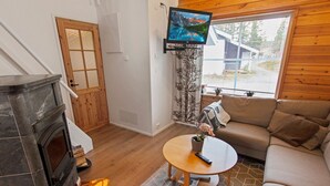 Ein gemütliches Wohnzimmer mit Kamin, einer Couch, einem Couchtisch und einem an der Wand befestigten Fernseher.