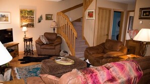 A cozy living room with a staircase, leather sofas, a coffee table, and a TV. - Cozy, Beautifully Furnished Condo 10  Minutes to Ski Resorts (Davis)