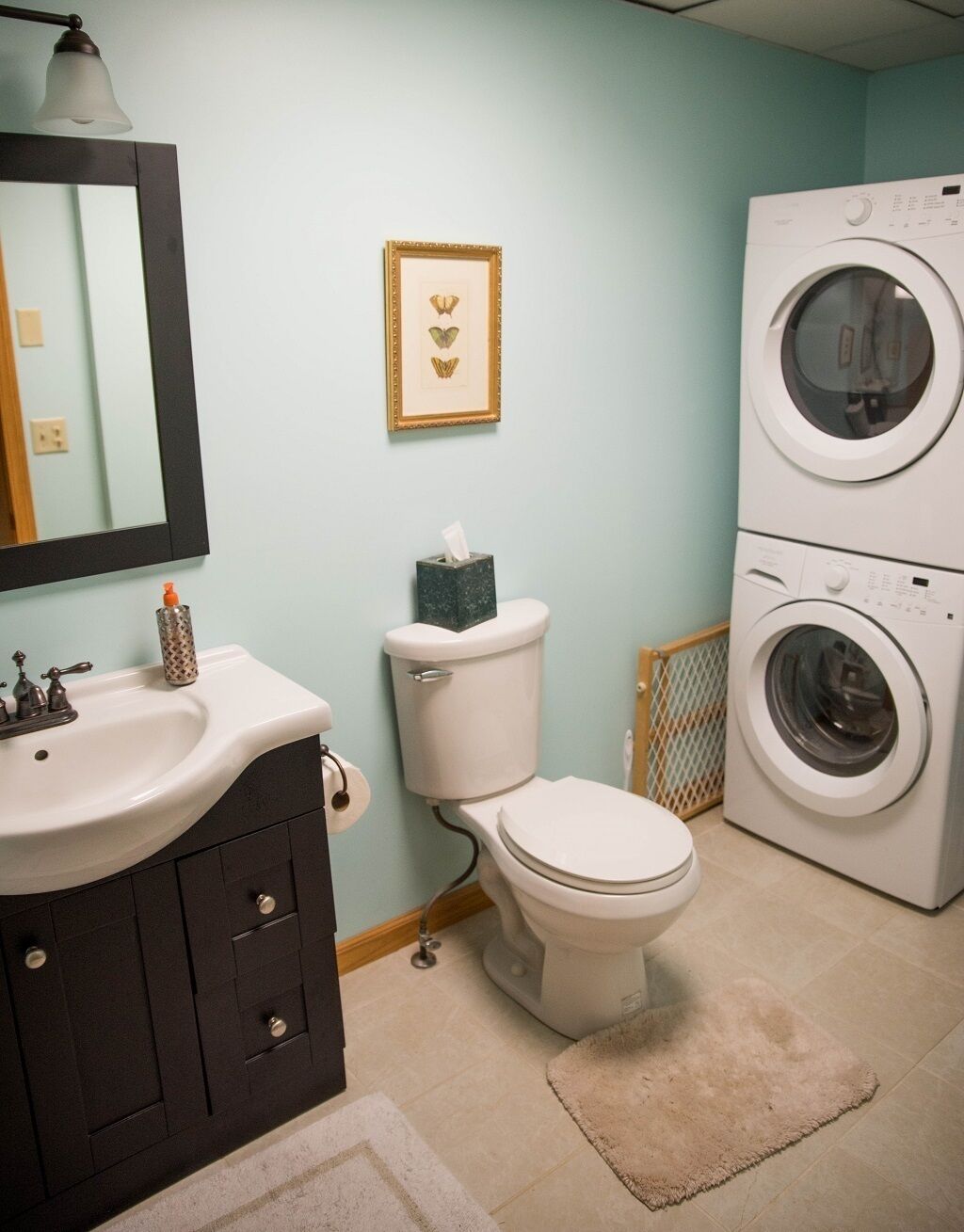 A bathroom with a sink, toilet, and stacked washing machines.