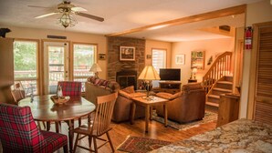 A cozy living room with a fireplace, a dining table with plaid chairs, a TV, and a staircase leading upstairs. - Cozy, Beautifully Furnished Condo 10  Minutes to Ski Resorts (Davis)
